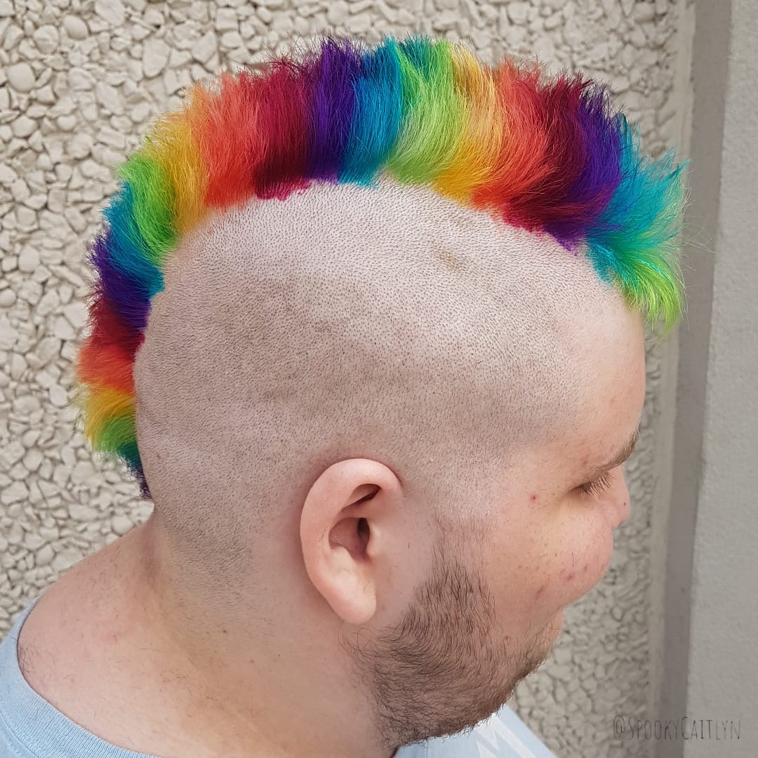 Side view of male customer with mohawk rainbow colour hair cut