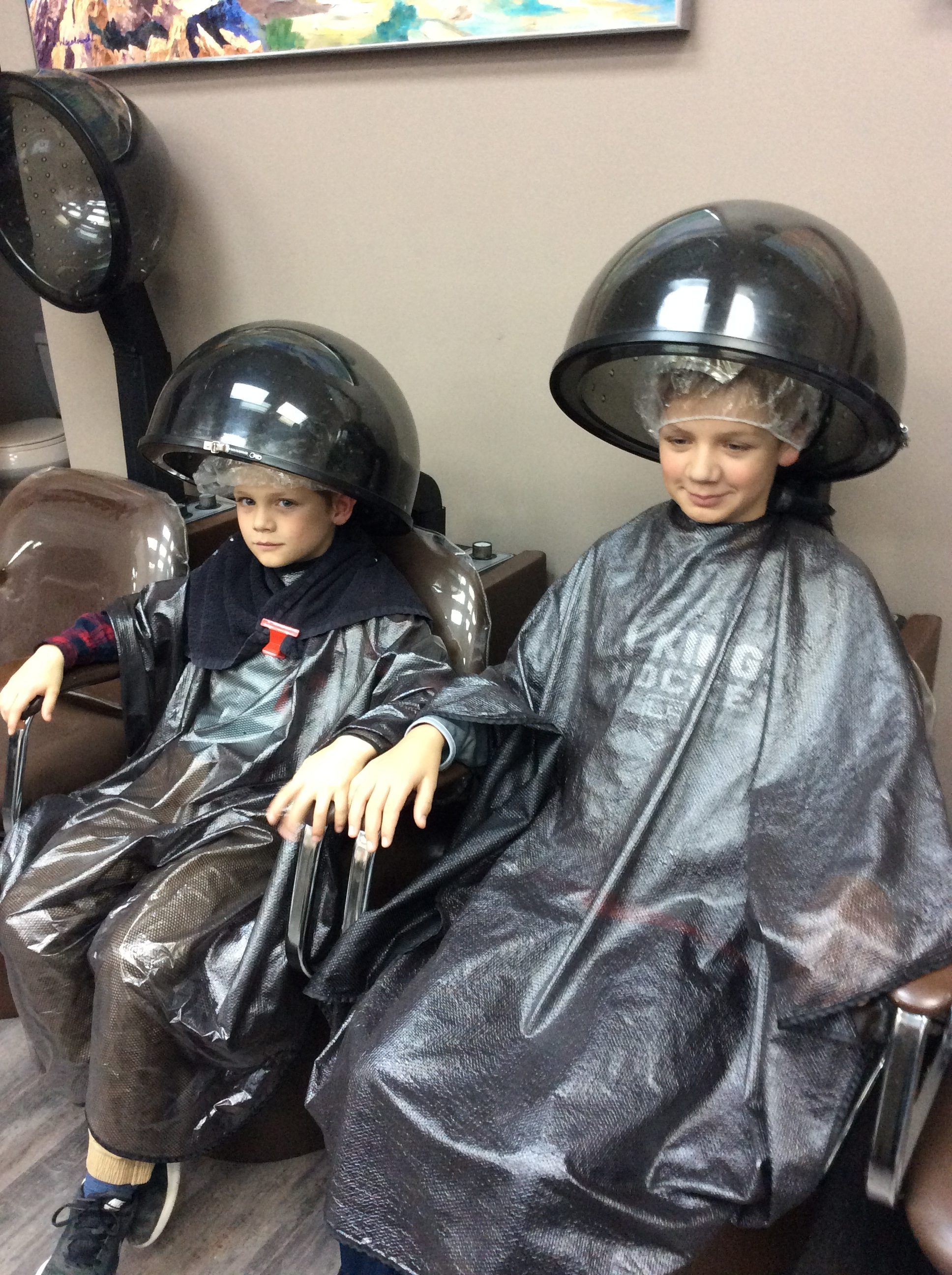 Young boys sitted under hair dryer at Hairstyle Inn