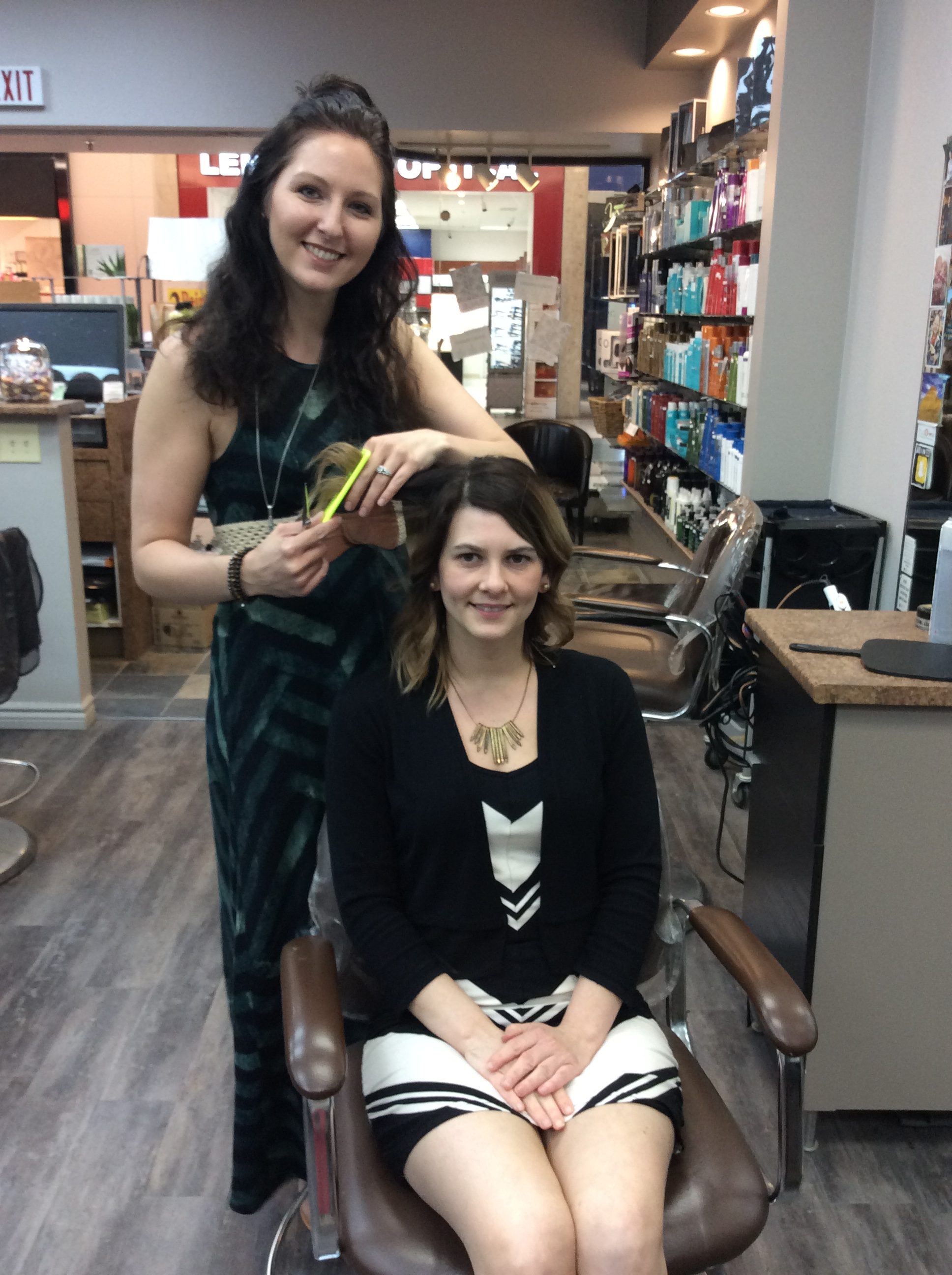 Hairstyle inn stylist posing for a photo with a customer's finished hair-do
