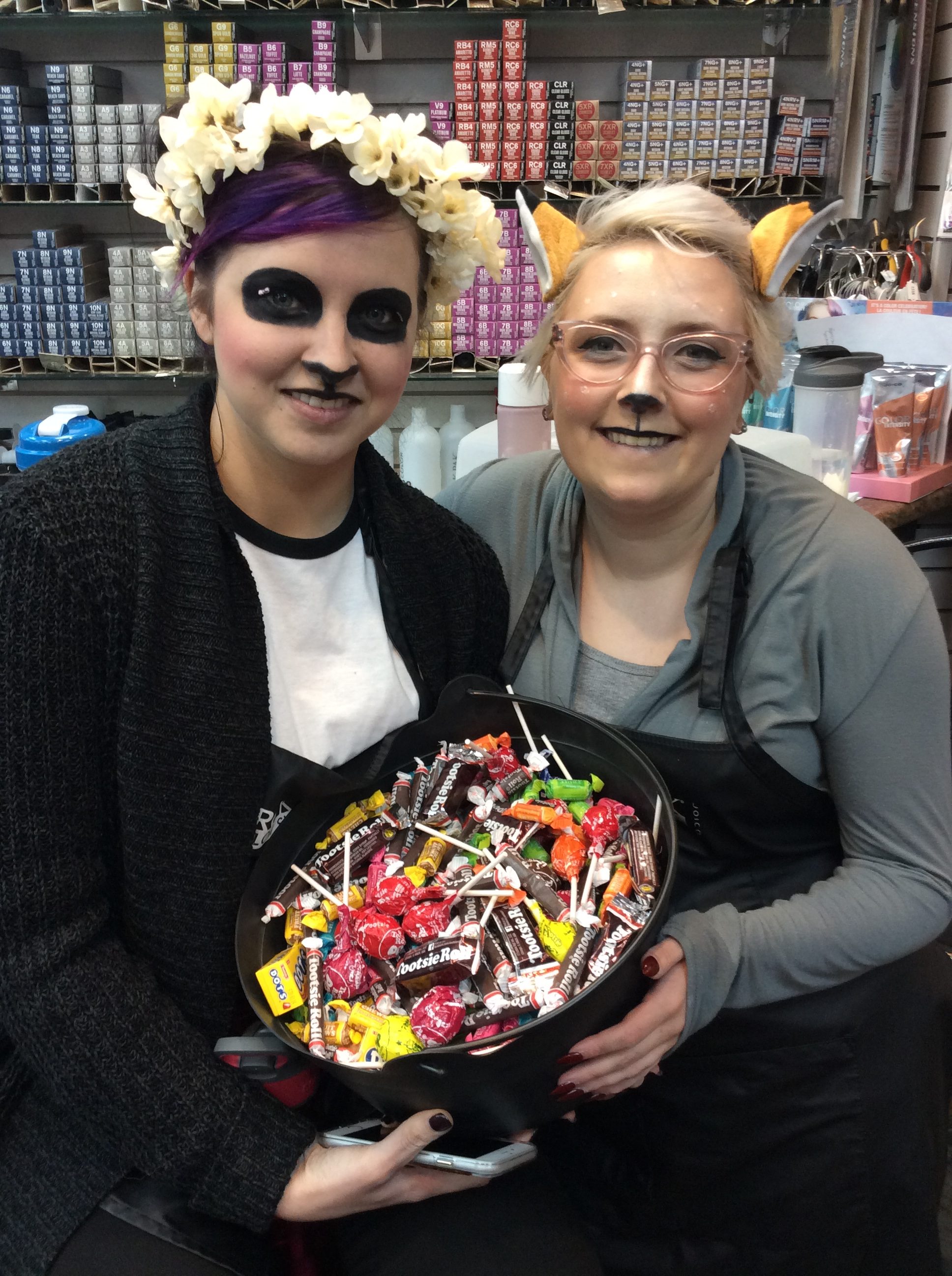Hairstyle inn stylists in Halloween costumes and a bowl of candies